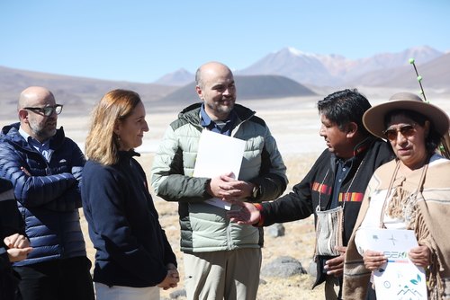 People in an outdoor meeting in a mountainous landscape.